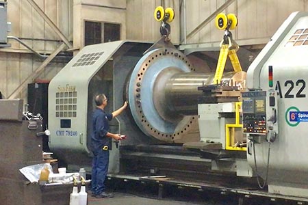 A man stands next to a large wind turbine machine part